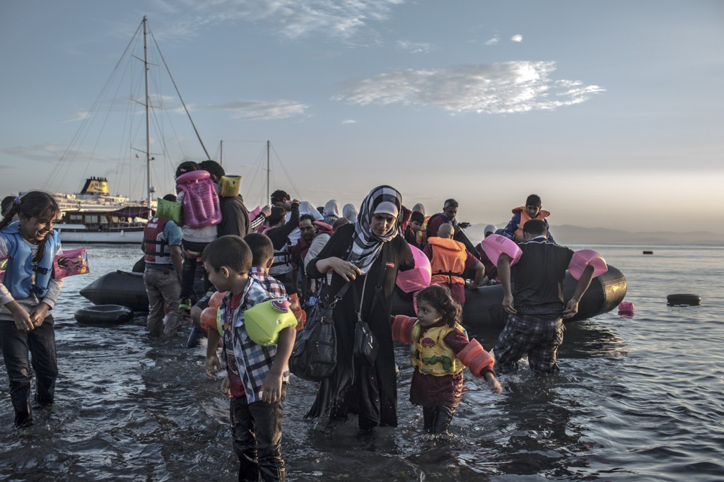 Syrian refugees wade ashore after arriving via a motorized inflatable raft with about 40 others on the island of Kos.